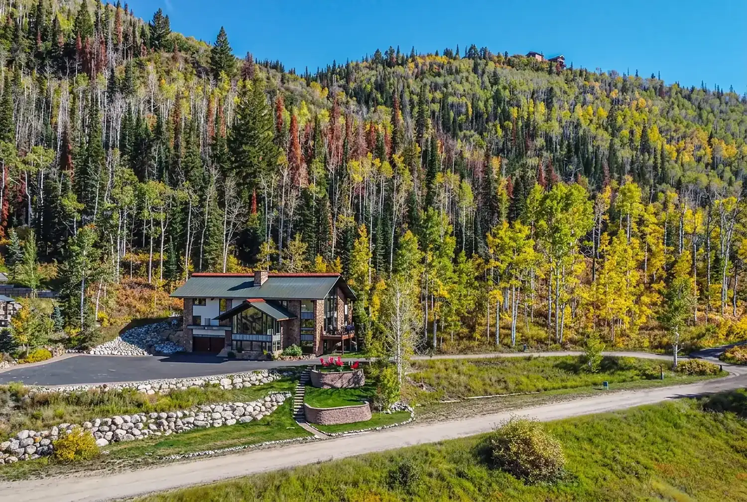 Mountain vacation home with a metal roof set below a hillside of golden fall aspens
