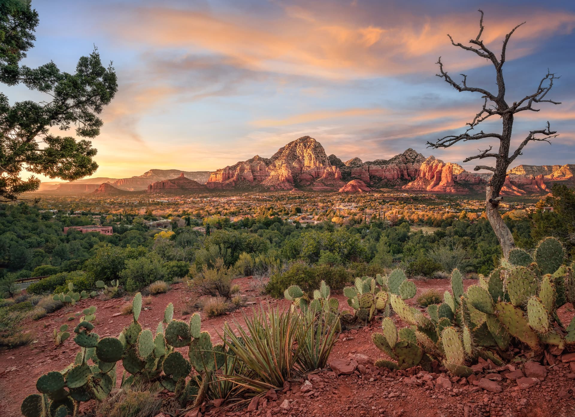 Red rock formations glowing at sunset above the junipers and cactus of Sedona, Arizona