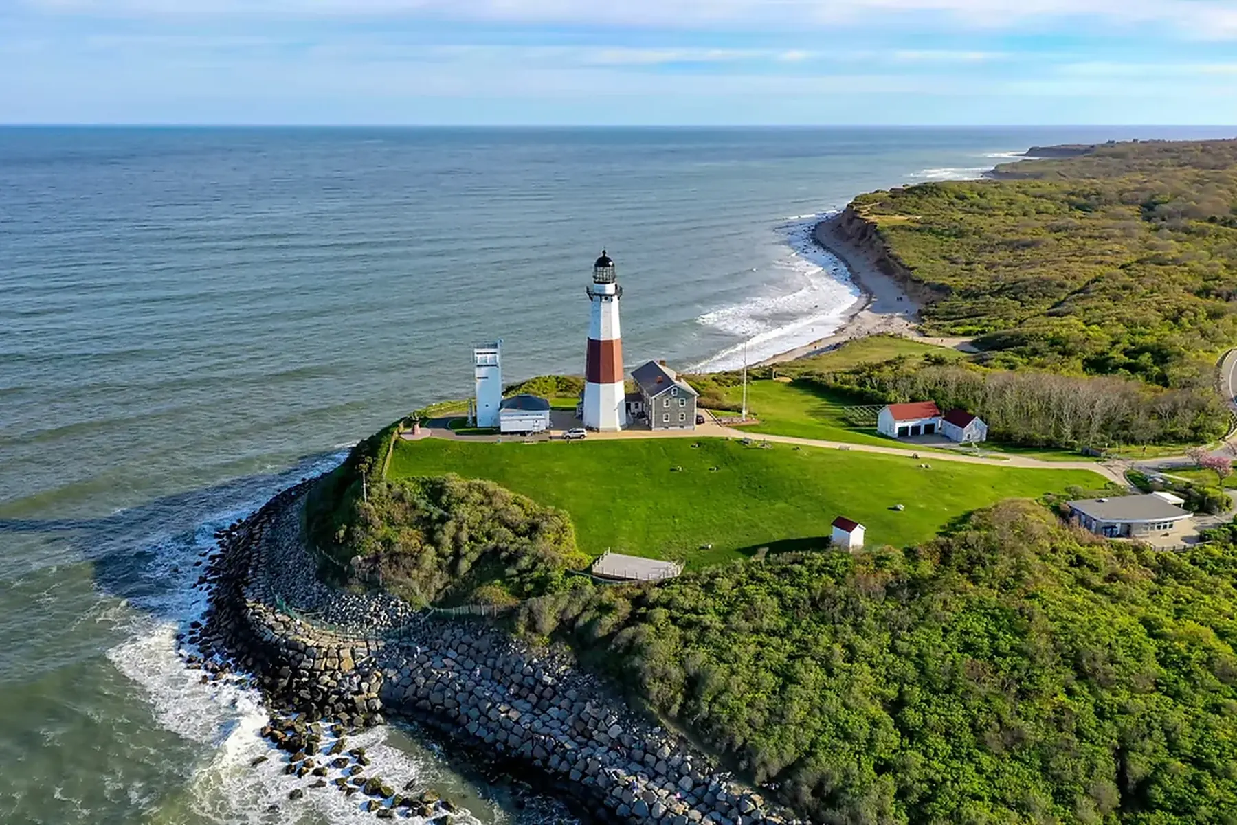 Montauk lighthouse on a green New York bluff above breaking Atlantic surf