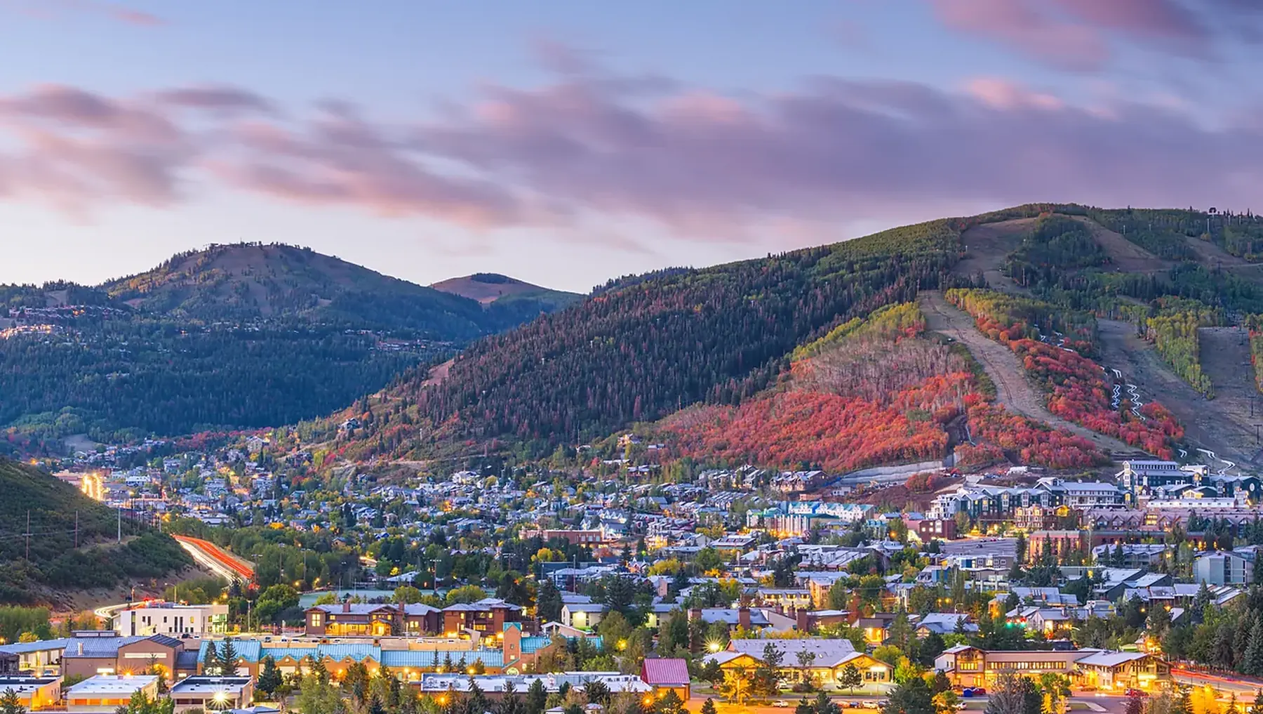 Utah mountain town in fall color with ski runs cut into the hillside above it